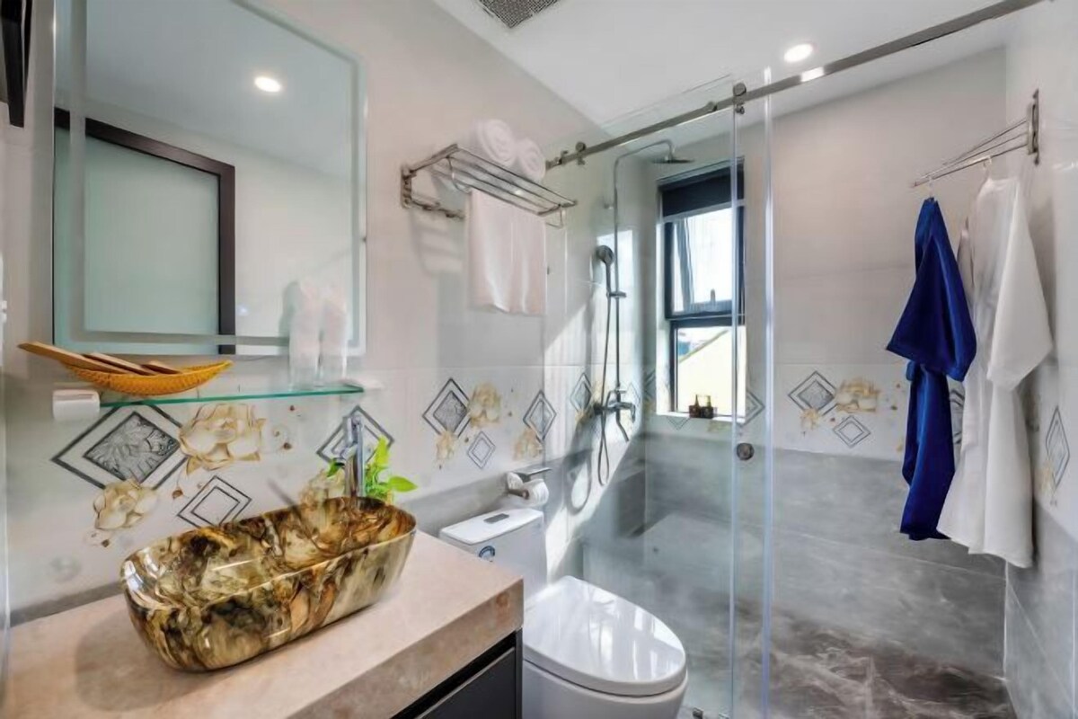 A modern bathroom with a glass shower enclosure, a marble sink, and a glass bowl.