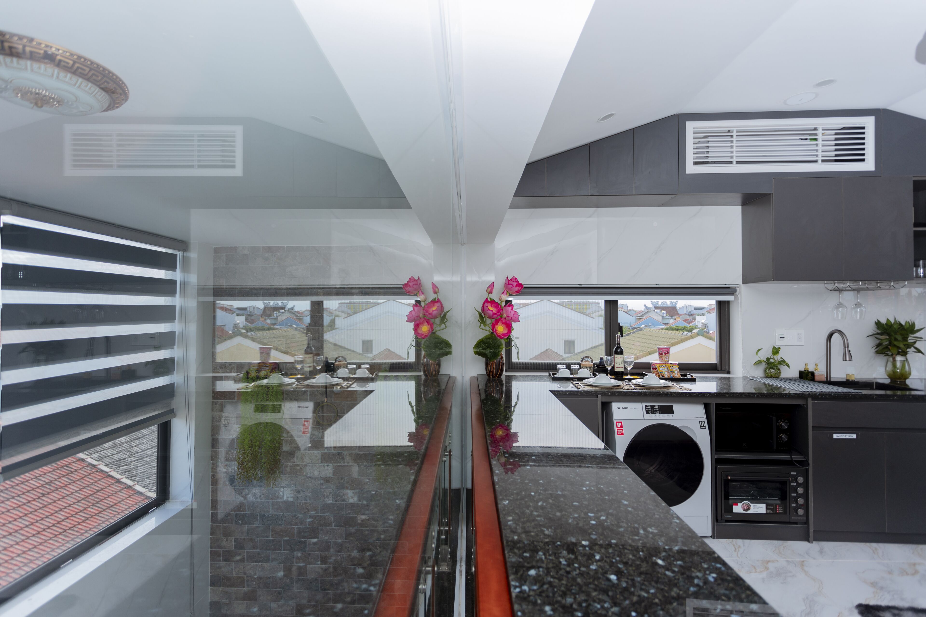 A modern kitchen with a built-in washer and dryer, a dining area with a glass partition, and a view of the cityscape.