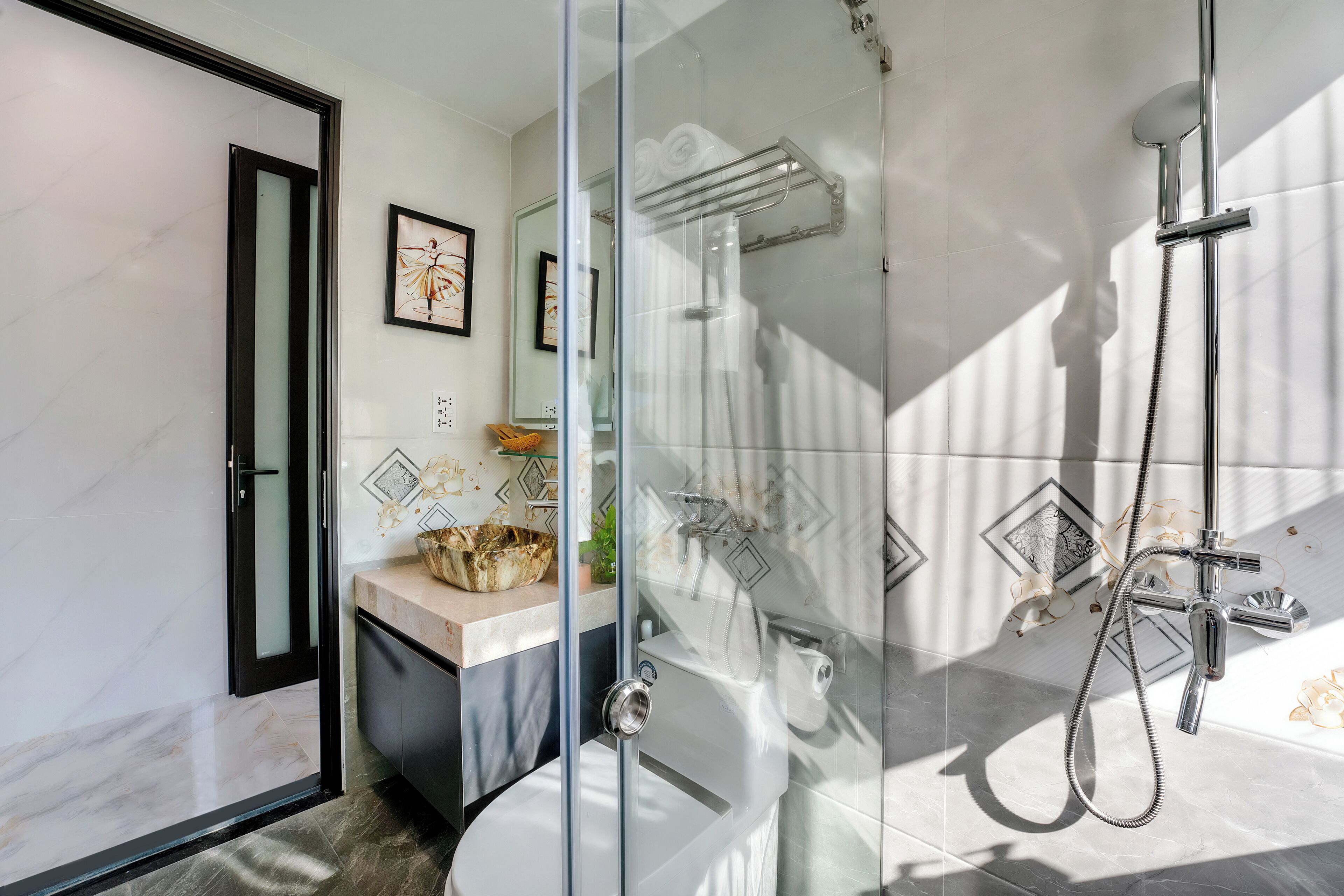 Une salle de bain moderne avec une douche à parois de verre, des toilettes et un lavabo agrémenté d’un récipient décoratif.