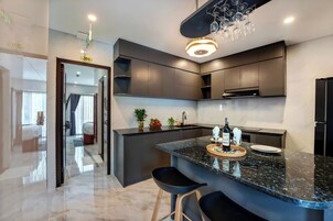 Cozinha moderna com armários escuros, bancada de granito e área de bar com banquetas.
