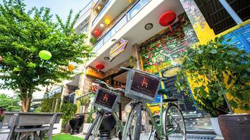 Un edificio con fachada colorida, una bicicleta estacionada al frente y un césped artificial verde.