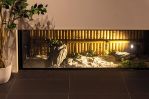 A rectangular aquarium with a bamboo backdrop, a rock formation, and aquatic plants. - WELLSTAY Osaka Shinimamiya (Osaka)