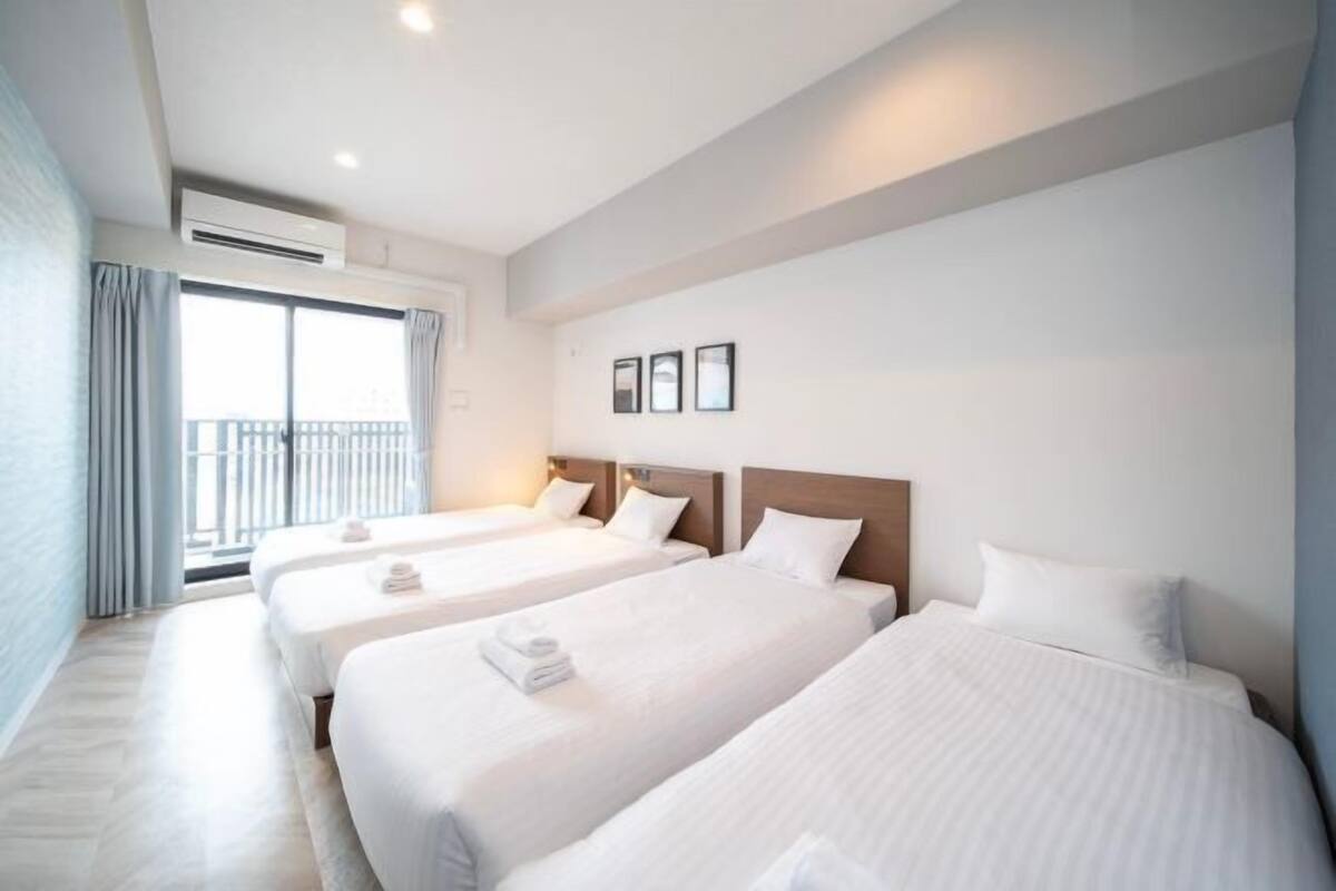 A hotel room with three beds, a balcony, and a view of the sea.