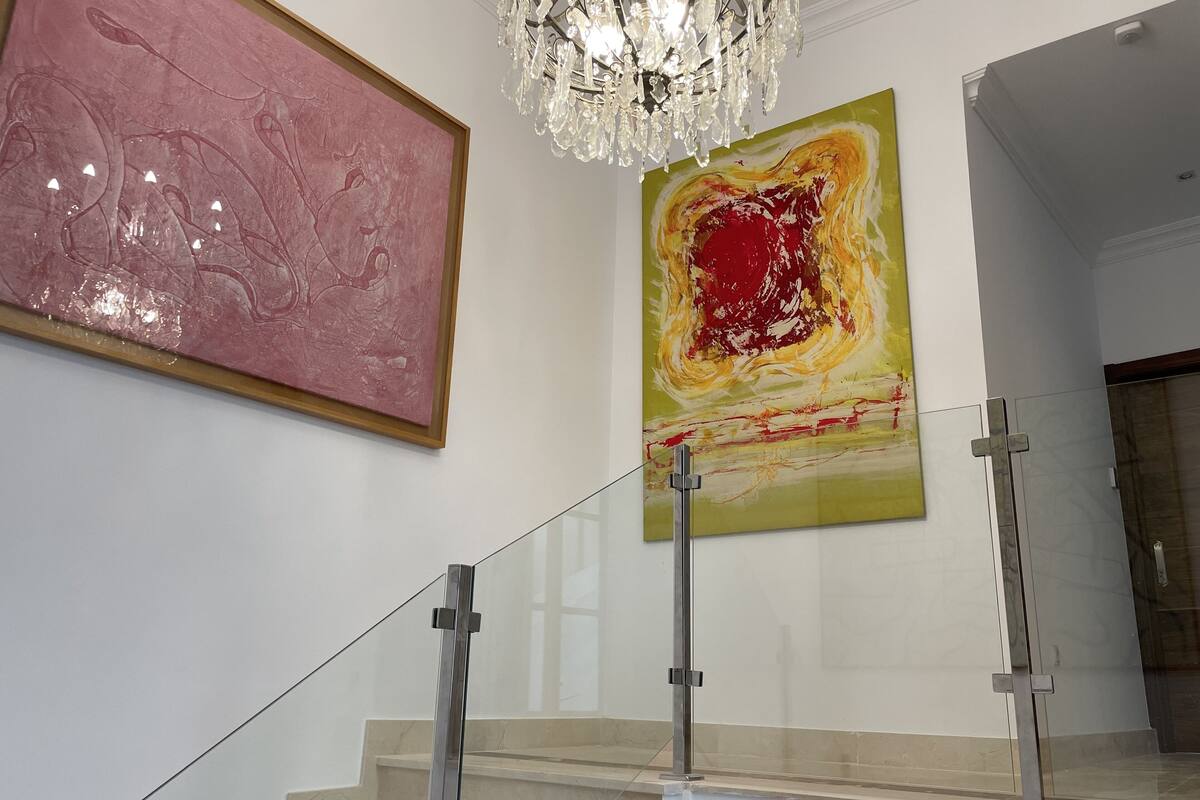 A staircase with glass railings and a chandelier above.