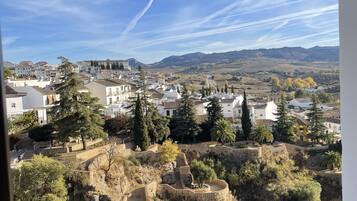 A view from a balcony overlooking a town with historic buildings, a clear sky, and a rocky landscape.