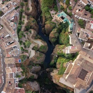 Vista aérea de un barrio residencial con casas escalonadas, un canal de agua estrecho y vegetación circundante.