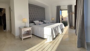 A modern bedroom with a large bed, bedside tables, and a view of the outside balcony. - Casa-Palacio Santa Pola (Ronda)