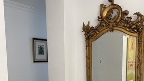 A hallway with a large ornate mirror, a framed picture on the wall, and a tiled floor. - Casa-Palacio Santa Pola (Ronda)