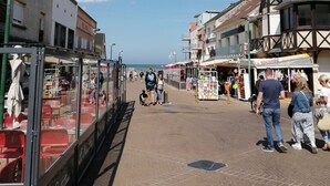 Ein gepflasterter Weg mit Geschäften und Gebäuden an beiden Seiten, der zum Meer führt.