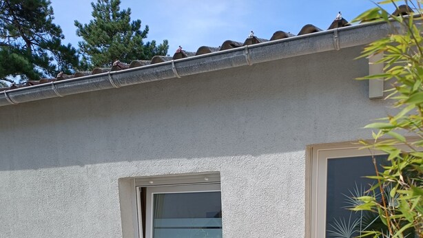 Eine Terrasse mit Tisch und Stühlen, ein kleines Fenster und eine Tür zu einem Außenbereich.