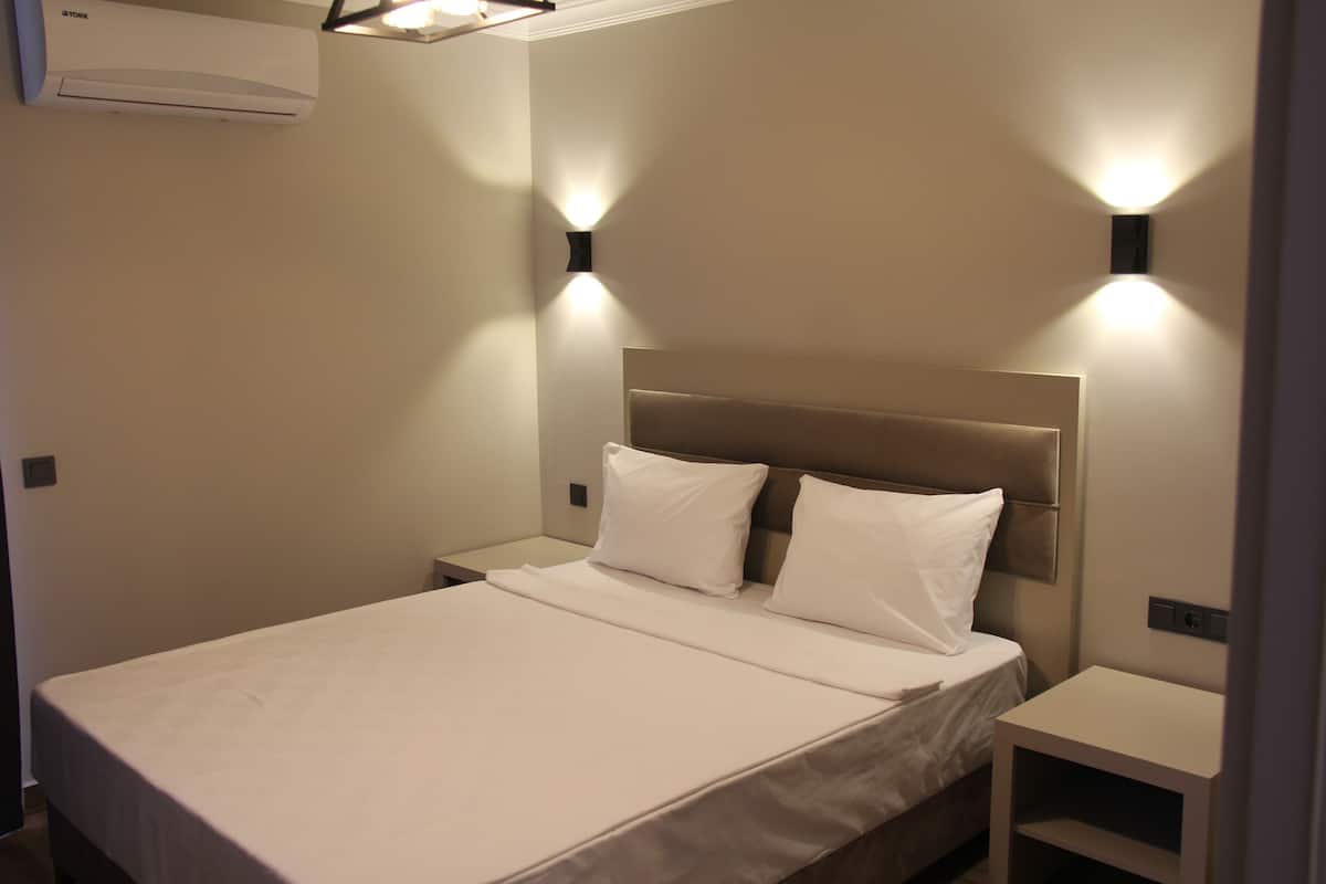 A hotel room with a bed, nightstands, and wall-mounted lighting.