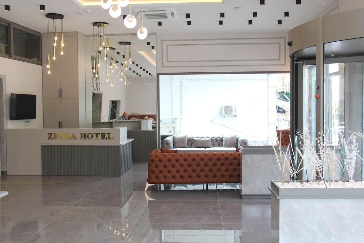 A hotel reception area with a modern design, a reception desk, a seating area, and a large window providing a view.