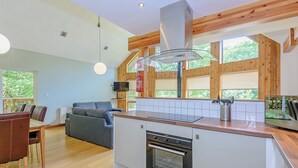 A modern kitchen with wooden beams, a built-in oven, and a dining area with a sofa and table. - A superbly appointed impressive two storey luxury lodge. (Llangollen)
