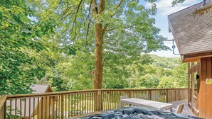 A hot tub on a wooden deck with a view of a forested area and a building with a wooden exterior. - A superbly appointed impressive two storey luxury lodge. (Llangollen)