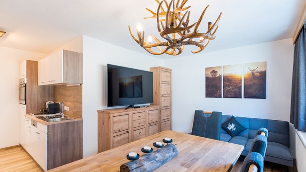 A modern living space with a wooden dining table, a television, and a sofa. - Apartment with Terrace (Oetz)