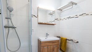 A bathroom with a shower, toilet, sink, and wooden cabinets. - Apartment with Terrace (Oetz)