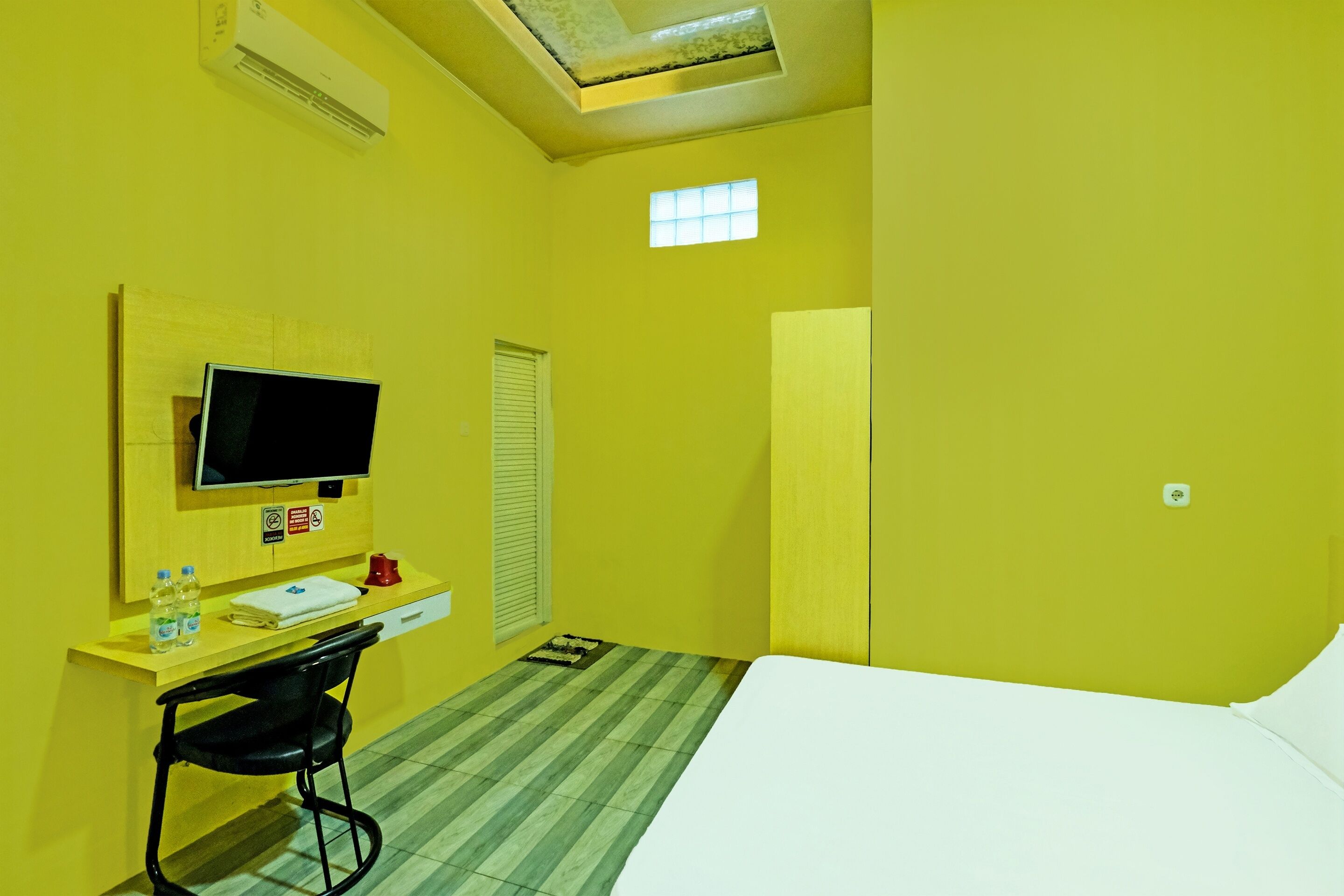 A hotel room with a bed, a desk with a chair, a television, and a window.