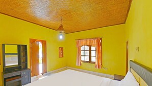Una habitación con una cama grande, un escritorio, un espejo y dos ventanas con cortinas.