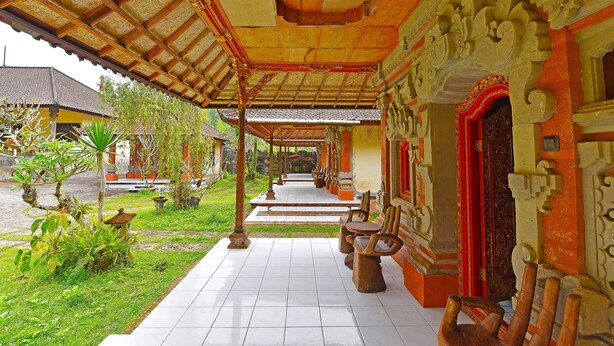 Un paseo techado con arquitectura tradicional, suelo de baldosas y asientos al aire libre.