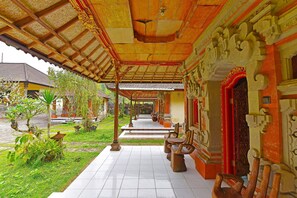 A covered walkway with traditional architecture, a tiled floor, and outdoor seating. - OYO 91100 Pondok Kusuma Wisata (Munduk)