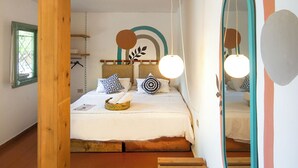 A bedroom with a wooden bed frame, a large mirror, and a staircase leading to an upper level. - Mayouli Nature Retreat (Batroun)