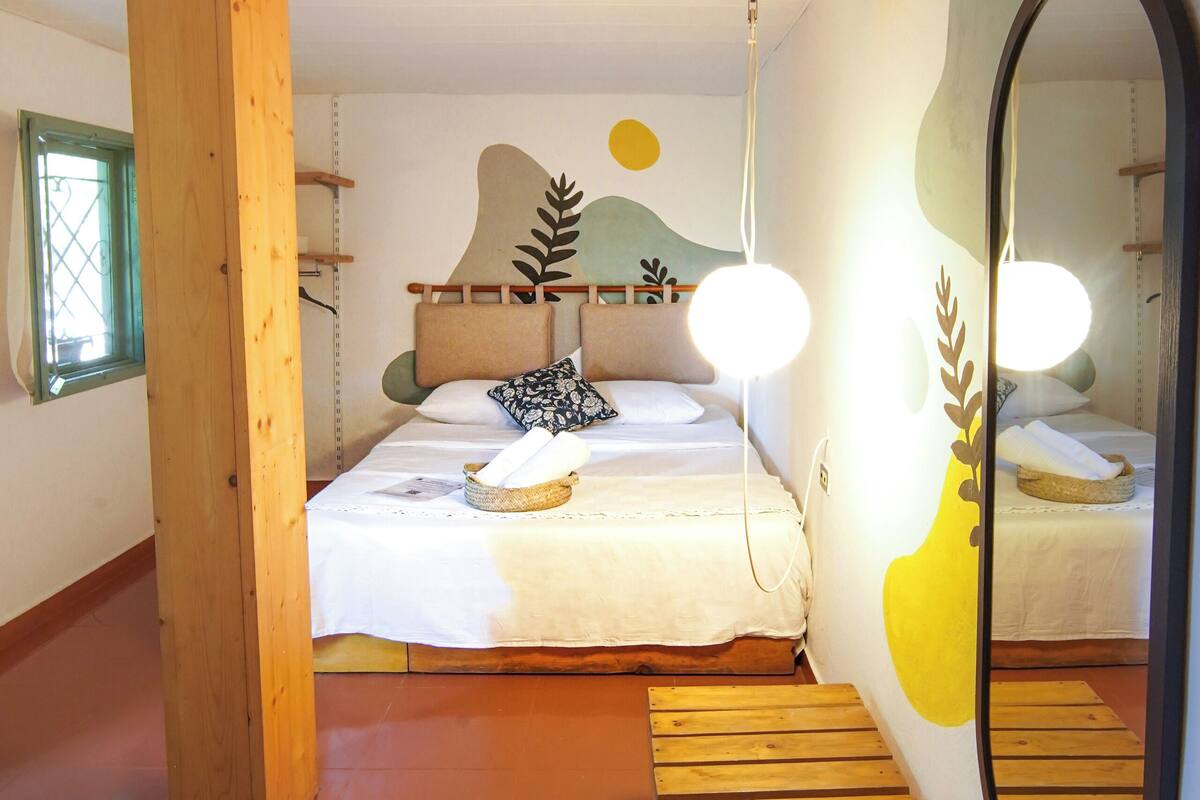 Quarto com estrutura de cama de madeira, um espelho grande e um banco de madeira.