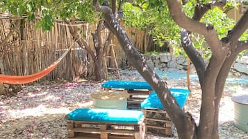 Un árbol con un banco debajo, rodeado de piedras y una cerca de bambú.