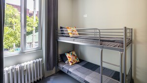 Dormitorio con literas, ventana, cortinas y radiador.