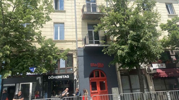 Un edificio con un restaurante 'DÖNERSTAG', un letrero que dice 'Bla Bla HOSTEL' y una puerta roja.