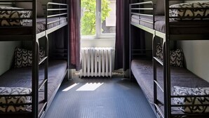 Un dormitorio con literas, una ventana con cortinas y un radiador.
