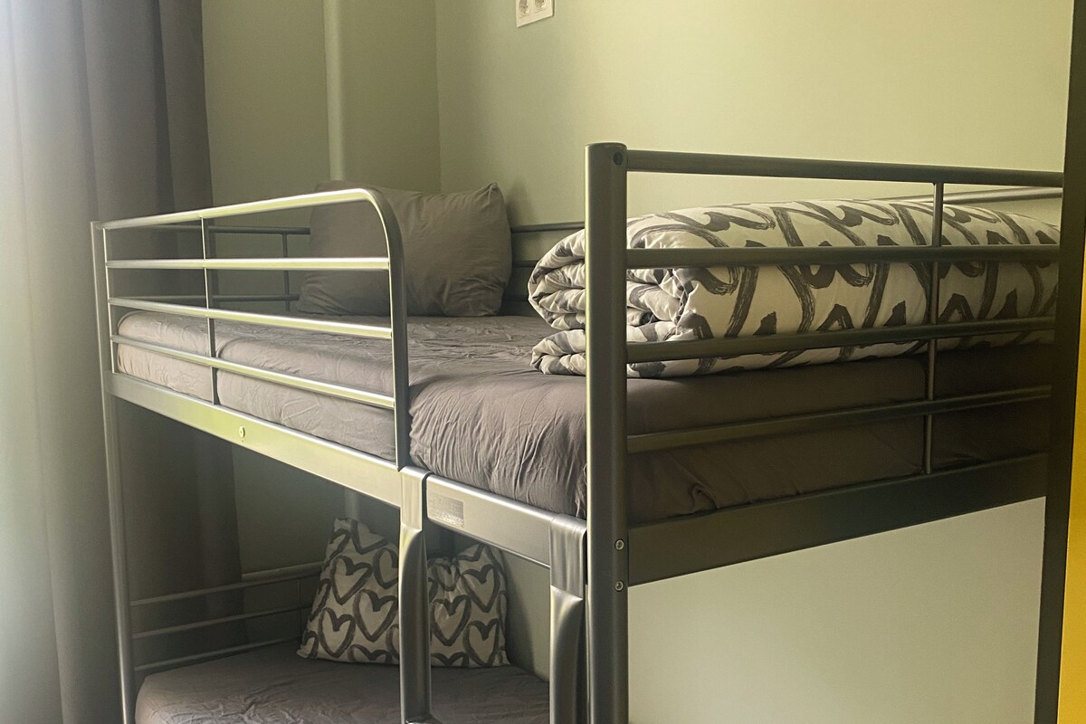 A bunk bed room with grey bedding and patterned pillows.