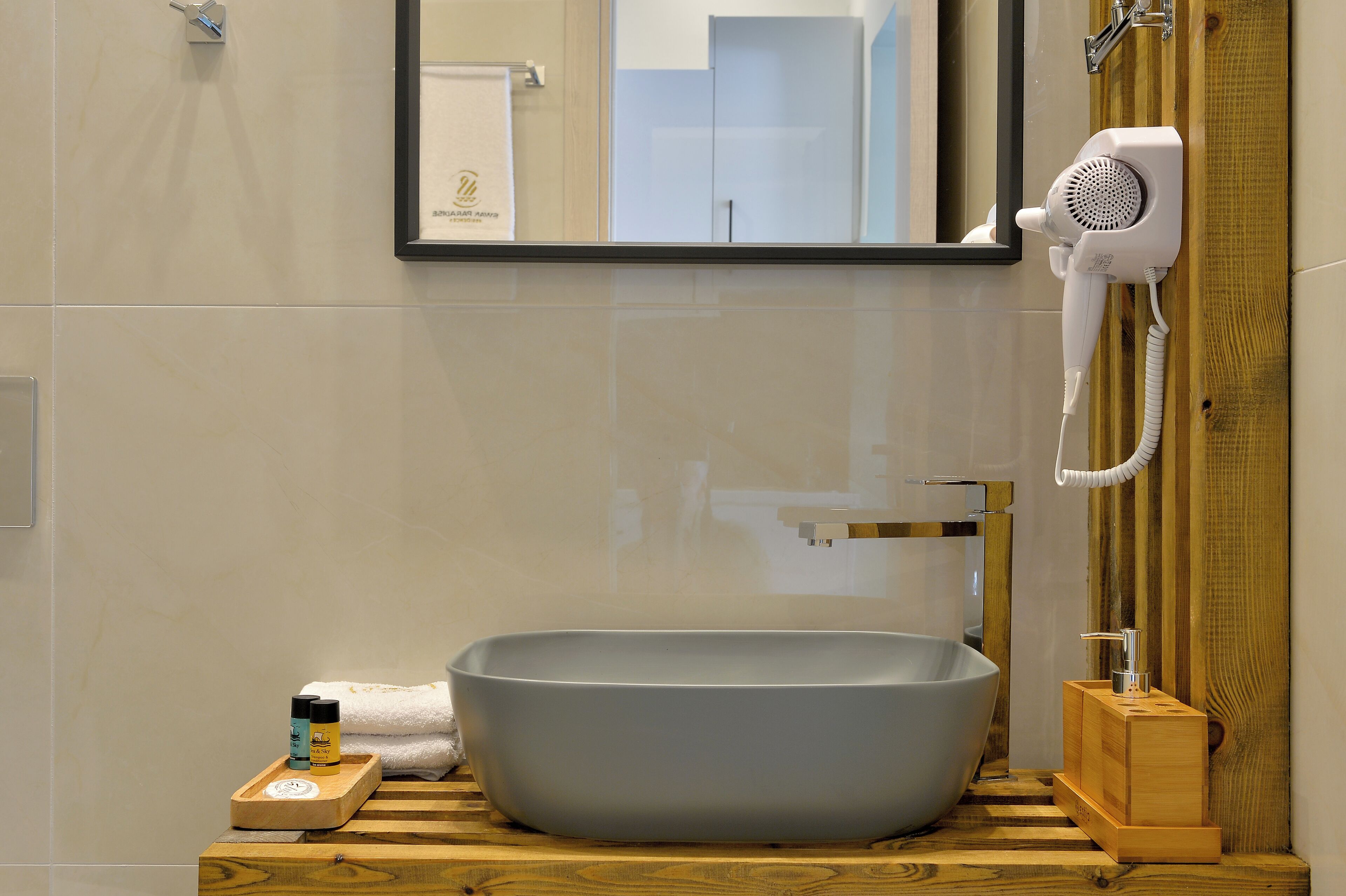Un baño con un lavabo de pedestal grande, un secador de pelo de mano y un jabonera de madera.