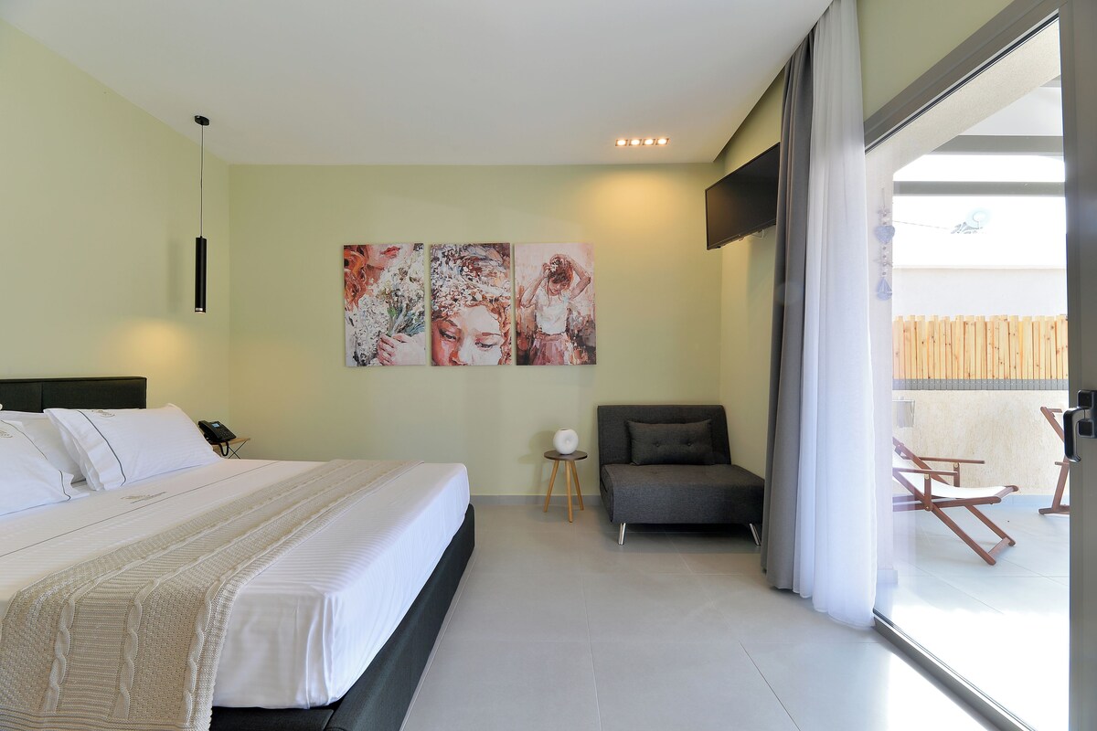 Una habitación de hotel moderna con una cama grande, un sofá y un balcón con valla de madera.