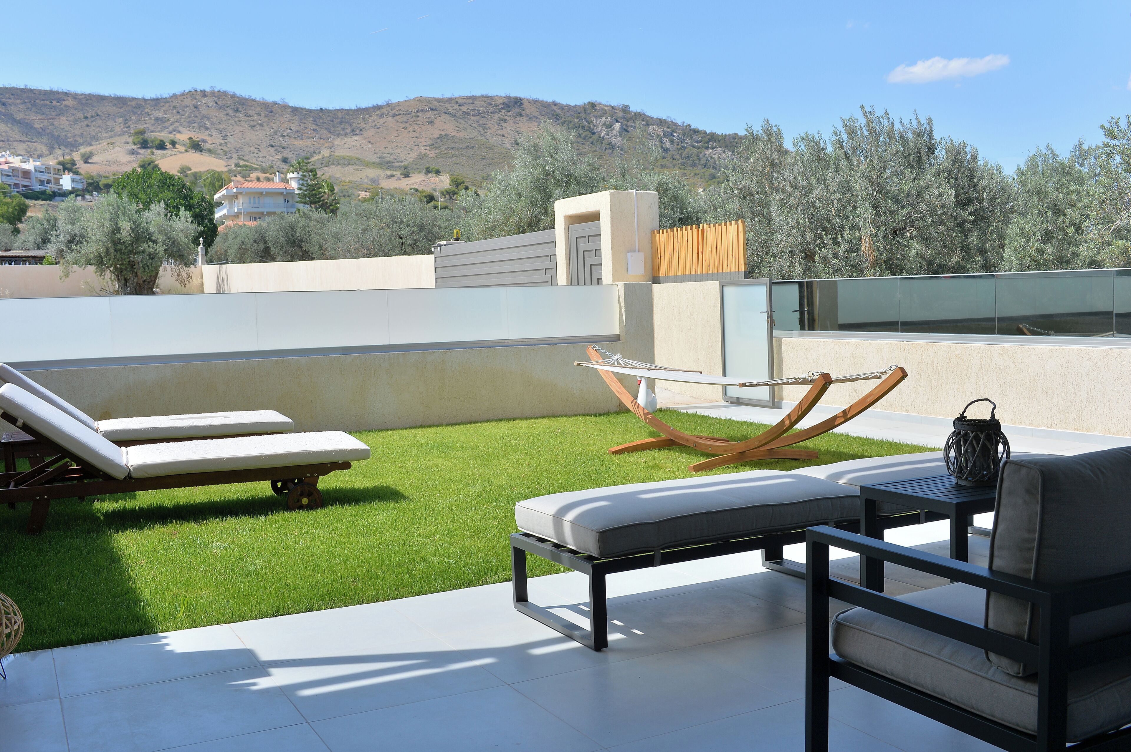 Una terraza en la azotea con césped, sillones de descanso y una mesa con una cesta.