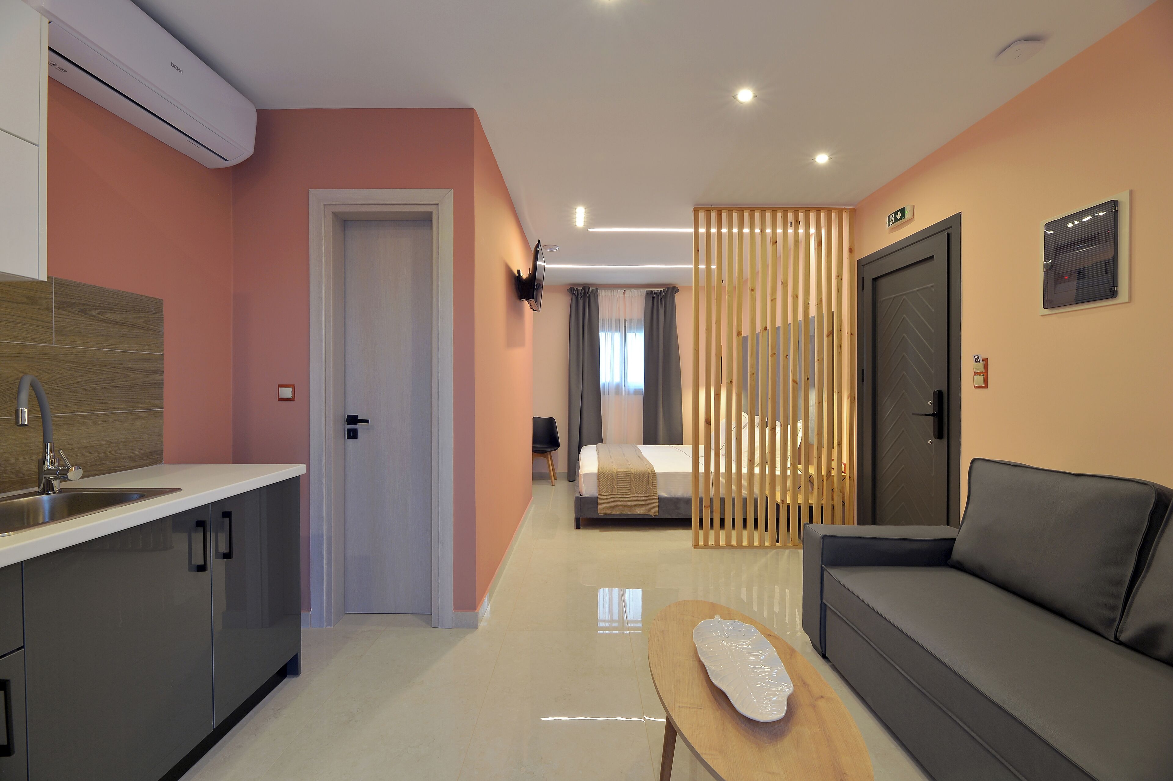 Une chambre d’hôtel moderne équipée d’une kitchenette, d’un canapé, d’une petite table et d’un lit.