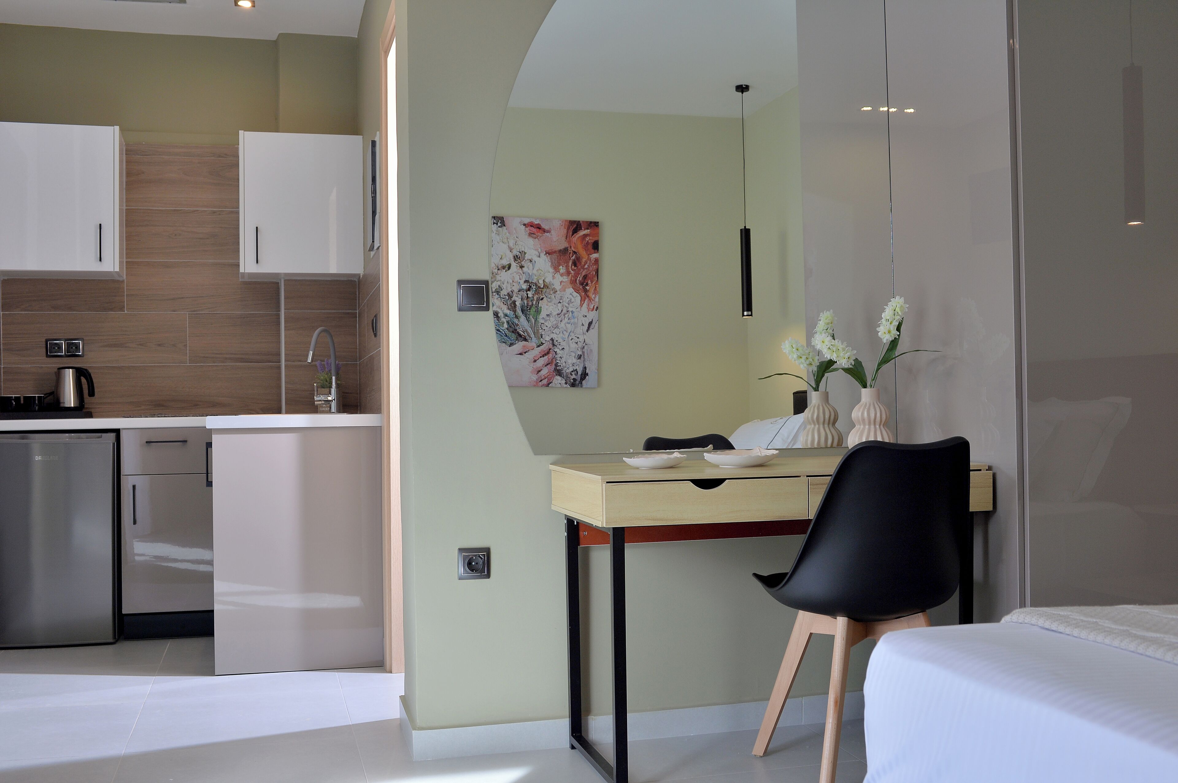 Moderni hotellihuone, jossa on pieni keittiö, ruokailutila ja sänky.
