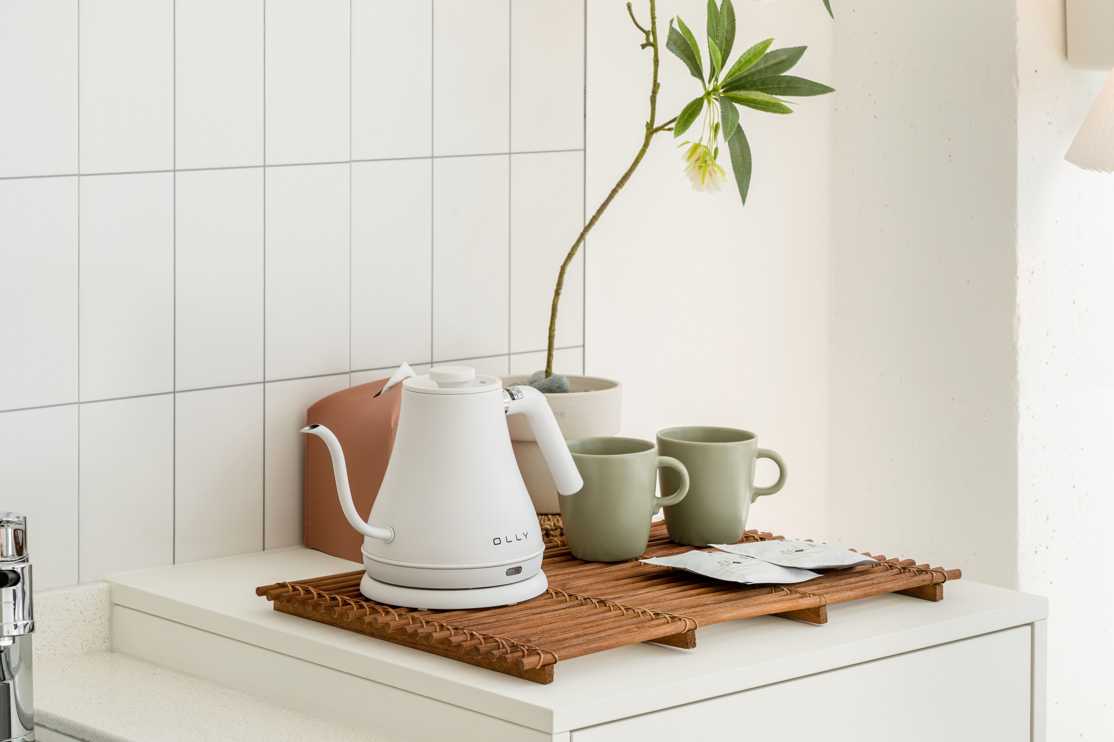 Eine Küchenarbeitsplatte mit Kaffeemaschine, einer Pflanze und einem Tablett mit Kaffeetassen und einer Teekanne.