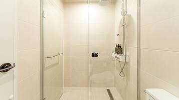A modern shower area with a glass door, a handheld showerhead, and a wall-mounted faucet.