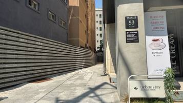A narrow urban alleyway with a modern building on the left and a sign for 'urbanstay' boutique ikseon on the right.