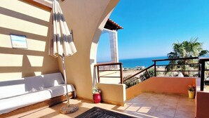 A balcony with a white sofa, a red vase with flowers, and a view of the sea. - Dreamy South Sea View Villa Residence with Pool - Upper Level (Frangokastello)