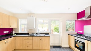 Une cuisine moderne avec des meubles en bois, un plan de travail noir, une cuisinière à gaz et une fenêtre qui laisse entrer la lumière naturelle.