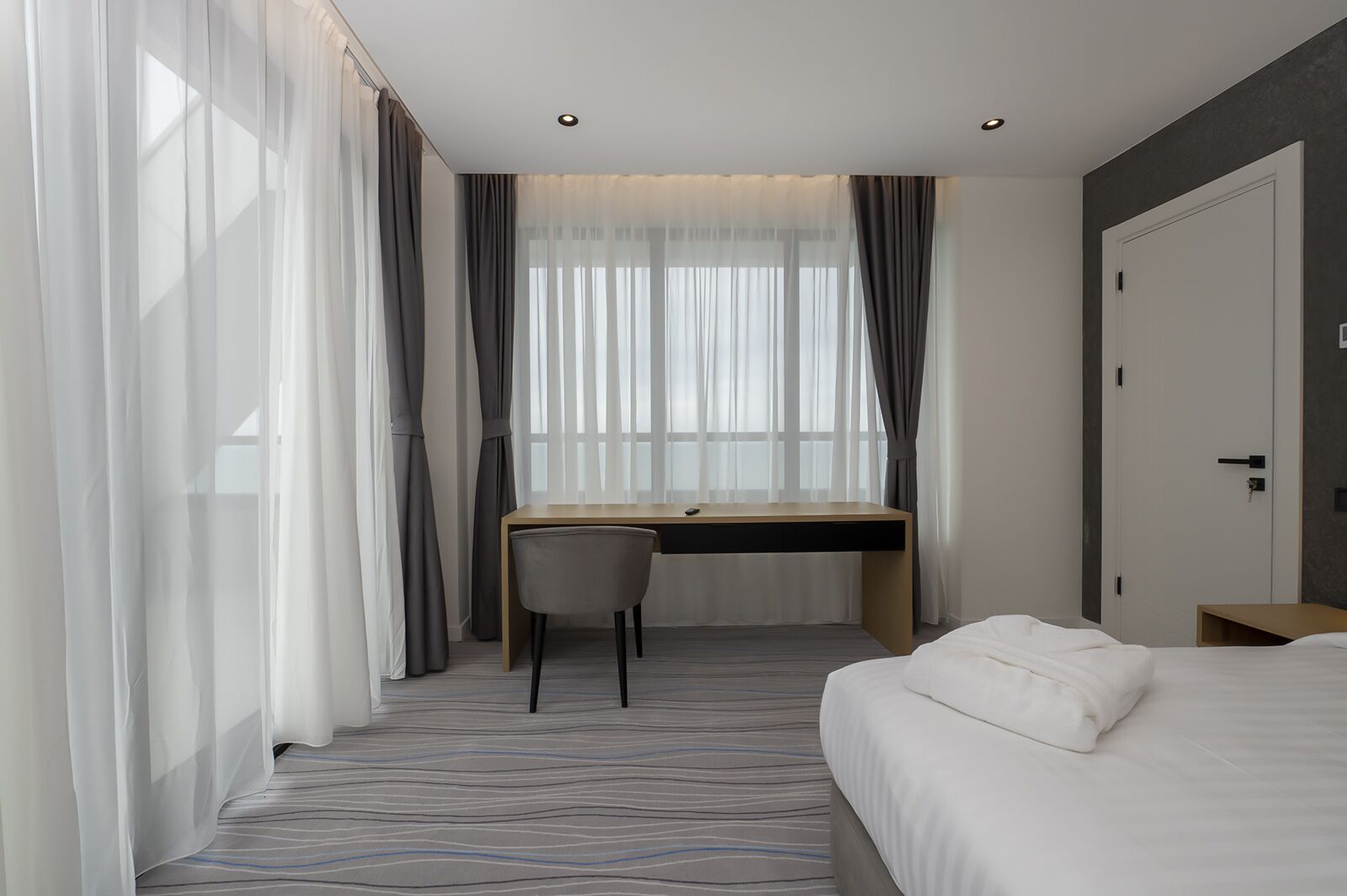 A hotel room with a bed, a desk, and a chair.