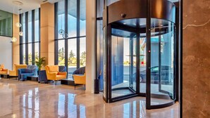 Un hall con puerta giratoria, amplias ventanas y zonas de estar.
