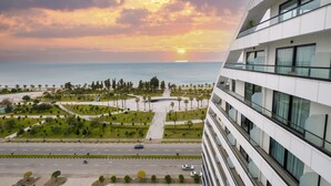 Un edificio moderno con vistas a un área ajardinada y al mar al atardecer.
