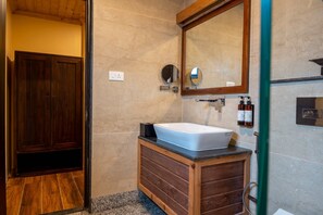 A bathroom with a wooden vanity, a white sink, a mirror, and a shower area. - Regenta Inn Gangtok (Gangtok)