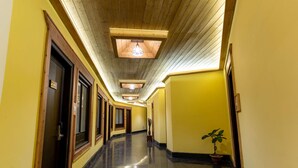 Un pasillo de hotel con techos de paneles de madera, paredes amarillas y piso pulido.