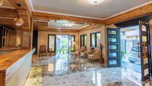 Un vestíbulo espacioso con suelo de mármol, techo de madera y una mesa de recepción.