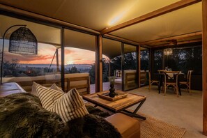 A modern interior with a sofa, dining table, and chairs. - The Enchanted Retreat | Glamping Tent (Havelock North)