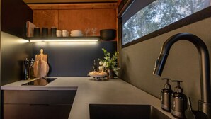 A modern kitchen with a sleek countertop, a built-in sink, and a window providing a view of trees.