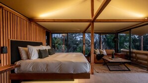 A modern bedroom with a large bed, a sofa, and a dining table.